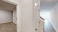 This well-appointed two-story home offers a clean, modern aesthetic defined by a neutral color palette, light hardwood-style flooring, and an abundance of natural light throughout. The main level centers around an open-concept kitchen that flows seamlessly into the living area. The kitchen is outfitted with white shaker-style cabinetry, light granite countertops, a center island with an undermount sink, and a full suite of stainless steel appliances including a range, microwave, dishwasher, and refrigerator. The adjacent living area features a ceiling fan and access to the outdoors through a glass door flanked by windows, filling the space with natural light. A convenient half bath with a pedestal sink is also located on the main level. The staircase leads to the upper floor, where a central hallway connects multiple bedrooms. The primary bedroom is generously sized with a ceiling fan, walk-in closet, and an en-suite bathroom featuring a dual-sink vanity with granite countertops. A second full bathroom on this level includes a single vanity with granite countertops and a shower-tub combo. Additional bedrooms offer ample space and closet storage. Throughout the home, recessed lighting, white trim, and consistent finishes contribute to a cohesive and inviting atmosphere.