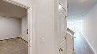 This well-appointed two-story home offers a clean, modern aesthetic defined by a neutral color palette, light hardwood-style flooring, and an abundance of natural light throughout. The main level centers around an open-concept kitchen that flows seamlessly into the living area. The kitchen is outfitted with white shaker-style cabinetry, light granite countertops, a center island with an undermount sink, and a full suite of stainless steel appliances including a range, microwave, dishwasher, and refrigerator. The adjacent living area features a ceiling fan and access to the outdoors through a glass door flanked by windows, filling the space with natural light. A convenient half bath with a pedestal sink is also located on the main level. The staircase leads to the upper floor, where a central hallway connects multiple bedrooms. The primary bedroom is generously sized with a ceiling fan, walk-in closet, and an en-suite bathroom featuring a dual-sink vanity with granite countertops. A second full bathroom on this level includes a single vanity with granite countertops and a shower-tub combo. Additional bedrooms offer ample space and closet storage. Throughout the home, recessed lighting, white trim, and consistent finishes contribute to a cohesive and inviting atmosphere.