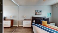 Located at 1718 Ximeno Ave in Long Beach, California, this single-story residence showcases a cohesive mid-century modern aesthetic carried throughout every room. The living area is generously proportioned, featuring hardwood-style flooring, neutral gray walls, and a textured ceiling. Natural light filters in through large windows fitted with horizontal blinds, creating a bright and welcoming ambiance. The space accommodates both lounging and casual seating areas with ease.

The kitchen is well-appointed with warm wood cabinetry, granite-style countertops, a double-basin sink, and stainless steel appliances including a gas range and over-the-range microwave. Adjacent to the kitchen, the dining area offers a comfortable nook with a window view and a ceiling fan overhead.

The bedrooms continue the home's warm, relaxed character, each outfitted with hardwood-style floors, ceiling fans, natural light from street-facing windows, and mirrored sliding closet doors that enhance the sense of space. The bathroom features a wood-toned vanity with granite countertops, a large wall mirror, and a full tub-shower combination. Throughout the home, consistent finishes and a carefully considered design palette create a comfortable and stylish living environment.