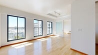 Located on the 11th floor at 541 S Spring St in the heart of Downtown Los Angeles, this one-bedroom, one-bathroom unit offers a bright and functional layout with modern finishes throughout. The open living area is anchored by warm hardwood flooring and a wall of large, black-framed windows that flood the space with natural light and frame sweeping views of the downtown Los Angeles skyline and surrounding cityscape. The galley-style kitchen is well-appointed with light wood cabinetry featuring glass-front upper panels, granite-toned countertops, stainless steel appliances including a refrigerator, electric range, and dishwasher, and tile flooring that transitions cleanly from the living areas. The bedroom continues the hardwood flooring and benefits from its own set of large windows offering additional city views and generous natural light. The bathroom is finished with tile flooring and features a combined shower and soaking tub enclosed by sliding glass doors with chrome hardware, offering a clean and practical design. The unit's crisp white walls and open layout create a minimalist aesthetic well-suited to urban living in one of Los Angeles's most vibrant downtown neighborhoods.