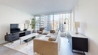 Located in the heart of downtown Montréal on Boulevard René-Lévesque Ouest, this modern 2-bedroom, 1-bathroom unit delivers a clean, contemporary aesthetic throughout its well-designed floor plan. The open-concept living and kitchen area serves as the centerpiece of the space, anchored by expansive floor-to-ceiling windows that flood the interior with natural light and frame striking views of the Montréal skyline. Light hardwood flooring runs throughout, complementing the crisp white walls and modern finishes.

The kitchen is outfitted with white cabinetry, marble-style backsplash, stainless steel appliances, and a peninsula with bar seating — ideal for casual dining or entertaining. Pendant lighting adds a polished touch to the space.

Both bedrooms are bright and thoughtfully designed. The primary bedroom features a sliding-door closet and a calm, neutral palette, while the second bedroom benefits from large windows with urban views. A dedicated closet provides additional storage.

The bathroom is finished with large-format grey tiles, a sleek glass-enclosed walk-in shower, a floating white vanity, and recessed lighting, offering a spa-like atmosphere. The overall design of the unit is cohesive, minimalist, and well-suited to urban living in one of Montréal's most vibrant neighborhoods.