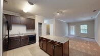 Located at 4110 Wake Hills Ln in Raleigh, NC, this well-appointed two-bedroom, two-bathroom single-story home offers a practical and comfortable layout. The open-concept living area seamlessly connects the kitchen, dining, and living room, creating an inviting communal space. The kitchen is highlighted by rich dark-wood cabinetry, granite-style countertops, a central island with additional storage, and black appliances including a dishwasher and refrigerator. Light tile flooring runs throughout the kitchen and dining areas, while plush carpet extends into the living room and bedrooms. Crown molding adds a refined touch to the main living areas. The spacious living room features a glass-paneled entry door and window, allowing natural light to fill the space. Both bedrooms are carpeted and well-sized, with the primary bedroom offering generous proportions and access to a large walk-in closet outfitted with wire shelving. The secondary bedroom includes a closet with double doors and a window overlooking the exterior. The bathrooms are clean and functional, featuring a tub/shower combination. Additional highlights include a dedicated laundry area with washer/dryer hookups, a utility room with a water heater, a pantry, and three closets throughout for ample storage.