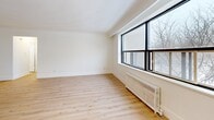 This 700 square foot apartment in Toronto offers a harmonious blend of modern design and practical living. The space boasts two bedrooms, including a primary bedroom of 170 square feet, providing ample room for comfort. Throughout the apartment, gleaming hardwood floors create a warm, inviting atmosphere, complemented by crisp white walls that amplify the natural light streaming through large windows.

The renovated kitchen showcases sleek white cabinetry, stainless steel appliances, and a functional layout, perfect for culinary enthusiasts. The bathroom, while compact, features a clean design with a wood vanity and a shower/tub combination. The living area is open and versatile, ideal for relaxation or entertaining.

Large windows in the bedrooms and living spaces not only flood the rooms with natural light but also offer picturesque views of the surrounding area, including bare trees in winter, suggesting a connection to nature despite the urban setting. Radiators beneath the windows provide efficient heating during colder months.

The apartment's layout is well-thought-out, with a central hallway connecting all rooms, ensuring easy flow and maximizing the use of space. Built-in closets in the bedrooms offer practical storage solutions. The overall design aesthetic is minimalist and contemporary, creating a canvas for personal style while maintaining a fresh, modern feel.