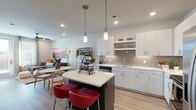 This single-floor residence showcases a thoughtfully designed open-concept layout that seamlessly connects the kitchen, dining, and living areas. The contemporary kitchen is a standout feature, equipped with stainless steel appliances including a dishwasher, range, microwave, and refrigerator. Crisp white cabinetry with modern hardware pairs with a neutral tile backsplash and quartz countertops. A dark-based center island with a white countertop and pendant lighting above provides casual seating and additional prep space. Light wood-style flooring runs throughout the main living areas, enhancing the bright, airy feel.

The living room offers a comfortable retreat with a ceiling fan, patio door access, and wall space suited for artwork. The dining area flows naturally between the kitchen and living room, completing the open-plan design.

Both bedrooms feature plush carpeting, ceiling fans, and multiple windows that invite generous natural light. The primary bedroom includes a walk-in closet. The shared full bathroom is well-appointed with a wide vanity, quartz countertop, a large frameless mirror, hardwood-style flooring, and a tub-shower combination, providing a clean, functional space throughout.