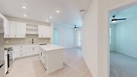 Located at 919 E Sligh Ave in Tampa, FL, this single-story, 2-bedroom, 2-bathroom unit offers a well-designed layout with modern finishes throughout. The open-concept kitchen serves as a central highlight, featuring white shaker-style cabinetry extending to the ceiling, a tiled backsplash, stainless steel appliances including a French door refrigerator, electric range, and microwave, as well as a central island with a white quartz countertop providing additional workspace and casual dining space. Light wood-style flooring runs through the main living areas, lending a clean and contemporary feel.

The primary bedroom features vaulted ceilings, plush carpet, and direct access to a walk-in closet with wire shelving systems. Its en-suite bathroom is finished with white cabinetry, quartz countertops, matte black fixtures, a large framed mirror, and a glass-enclosed walk-in shower. The second bedroom is carpeted, includes a ceiling fan, and benefits from a natural light through a window with outdoor views. A second walk-in closet with wire shelving provides additional storage. One room features French doors that invite natural light and outdoor access. The unit's bright, neutral palette creates a cohesive and welcoming ambiance throughout.