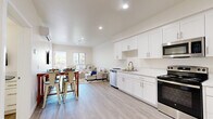 This well-appointed one-bedroom, one-bathroom residence at 5310 Adobe Falls Rd in San Diego, CA offers a thoughtfully designed single-level layout with a clean, modern aesthetic throughout. The open-concept kitchen and living area serves as the heart of the home, featuring light-toned luxury vinyl plank flooring, recessed lighting, and a bright, airy atmosphere enhanced by natural light from large windows. The kitchen is outfitted with crisp white shaker-style cabinetry, light quartz countertops, and a full suite of stainless steel appliances including a refrigerator, range, microwave, and dishwasher — providing both style and functionality. The living area flows seamlessly from the kitchen and dining space, offering room for comfortable seating and direct access to an outdoor patio, where views of the surrounding hillside can be enjoyed. The bedroom is a calm, well-lit retreat with vertical blinds filtering soft natural light and ample space for a full-sized bed and furnishings. The bathroom features a full tub-shower combination, a white vanity with a stone-topped sink, and coordinating light wood-look flooring. Neutral tones and clean lines carry throughout the entire residence, creating a cohesive and inviting atmosphere ideal for comfortable San Diego living.