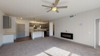 Located at 3281 Tutt Blvd in Colorado Springs, Colorado, this single-floor unit offers a thoughtfully designed open-concept layout that seamlessly connects the living, dining, and kitchen areas. The living space features plush carpeting, a ceiling fan, and a sleek wall-mounted electric fireplace, creating a comfortable and modern ambiance. Natural light filters through large windows, enhancing the bright, neutral palette throughout.

The kitchen is a standout feature, equipped with gray shaker-style cabinetry, white quartz countertops, a subway tile backsplash, and a full suite of stainless steel appliances including a refrigerator, range, microwave, and dishwasher. A central island with pendant lighting above adds both workspace and visual appeal, while wood-look plank flooring anchors the area with a warm, contemporary feel.

The bedrooms are generously sized, each with plush carpet, ceiling fans, and large windows that bring in ample natural light. The bathroom is well-appointed with dual-sink vanity featuring blue-gray cabinetry, a wide frameless mirror, white quartz countertops, and wood-look flooring, complemented by a tub-shower combination.