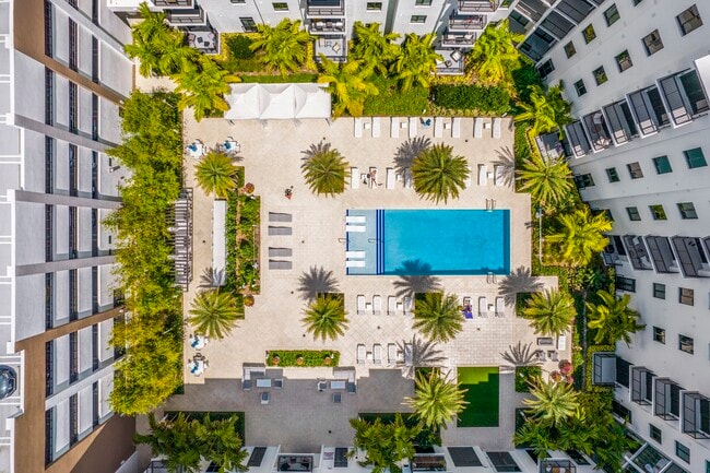 Resort-style pool deck surrounded by lush landscaping and sun-soaked spaces. - SoLe Mia Rentals