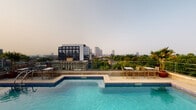 Situated in the heart of Columbus, Ohio, this property at 797 N Wall St offers a remarkable rooftop experience that sets it apart. The standout feature is an expansive rooftop pool with a striking blue-tiled surround and a shallow wading ledge, perfectly positioned to take in sweeping, unobstructed views of the Columbus skyline. High-top bar seating and chairs are arranged along the perimeter, making the rooftop an ideal setting for both casual lounging and social gatherings. The skyline backdrop, framed by a mix of urban architecture and lush tree canopies, creates a vibrant yet serene atmosphere, especially during golden hour. A glass railing system ensures the views remain uninterrupted while maintaining safety at elevation. The interior spaces include windowed rooms fitted with horizontal blinds, allowing for adjustable natural light. The single-floor layout offers a practical and accessible flow throughout the property. Overall, this space combines urban convenience with elevated outdoor amenities, making it a distinctive offering in the Columbus, OH market.