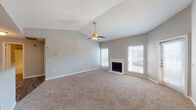 Located at 7935 Pipers Creek St in San Antonio, Texas, this single-floor residence offers a thoughtfully designed layout with a warm, neutral color palette throughout. The expansive living room is a standout feature, boasting vaulted ceilings, a ceiling fan with light fixture, plush wall-to-wall carpeting, and a classic white-mantled fireplace flanked by multiple windows that invite abundant natural light. A dedicated exterior door provides convenient access from the living area. The kitchen is efficiently laid out with dark cabinetry, light granite-style countertops, wood-look vinyl flooring, a tile backsplash, and a full suite of black appliances including a range, microwave, and refrigerator. The bedrooms are generously sized, each equipped with ceiling fans and soft carpeting. The primary bedroom connects directly to a well-appointed bathroom featuring navy cabinetry, a granite-style vanity, wood-look flooring, and built-in open shelving for additional storage. A spacious walk-in closet with wire shelving and hanging rods provides ample storage. The secondary bathroom includes a tub-shower combination, granite-style vanity, and matching dark cabinetry, maintaining a consistent design aesthetic throughout the home.
