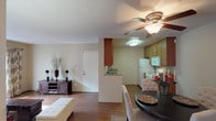 This single-story residence at 715 Ash Lanes in San Marcos offers a well-organized layout with interconnected living spaces designed for comfortable everyday living. The living room serves as the heart of the home, featuring warm wood-look flooring, neutral-toned walls, and a ceiling fan overhead. A sliding glass door floods the space with natural light and provides outdoor access, while a wall-mounted air conditioning unit ensures year-round comfort.

Adjacent to the living area, the dining space accommodates a round table beneath a ceiling fan, positioned conveniently beside the kitchen for easy flow during meals. The kitchen is efficiently designed with warm wood cabinetry, granite-style countertops, and white appliances including a refrigerator, range, microwave, and dishwasher. Wood-look flooring continues throughout, tying the common areas together cohesively.

The bedroom is carpeted and offers a tranquil retreat, featuring a large window with outdoor views and a sliding closet door providing ample storage. The bathroom includes a warm wood vanity with a granite-style countertop, a framed mirror with overhead lighting, and a full tub-shower combination, all finished with light-toned tile flooring.