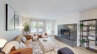 This thoughtfully designed single-floor home offers four bedrooms and two bathrooms within a well-utilized, comfortable footprint. The open-concept layout seamlessly connects the living, dining, and kitchen areas, creating a bright and cohesive social space. Light hardwood flooring runs throughout the main areas, complemented by neutral walls that enhance the sense of airiness.

The living room is a standout feature, anchored by a striking floor-to-ceiling tiled fireplace with a dark metallic finish, large windows, and a glass-paned door that invites ample natural light and outdoor views. The dining area is accented by a modern brass chandelier and large windows, adding an elegant yet functional touch. The kitchen is well-equipped with two-tone grey and white shaker cabinetry, white quartz countertops, gold hardware, stainless steel appliances, and a pendant light above the sink.

The bedrooms feature plush carpeting and generous closet storage, including built-in shelving. The bathrooms are finished with clean white vanities and classic fixtures. A dedicated laundry room with a full-size washer and dryer adds everyday convenience. The home's cohesive, modern aesthetic and functional layout make it a highly practical and attractive living space.