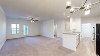 Located at 4343 Warm Springs Rd in Columbus, Georgia, this single-story 2-bedroom, 2-bathroom home offers a thoughtfully designed open-concept layout ideal for comfortable everyday living. The combined kitchen and living room serves as the heart of the home, where a peninsula with granite countertops and a built-in sink connects the kitchen to the carpeted living area. The kitchen is equipped with white cabinetry, black appliances including a refrigerator, microwave, and range, and is illuminated by a skylight panel and recessed lighting. The living room features a ceiling fan and access to a private exterior door. The generously sized primary bedroom includes a ceiling fan, plush carpet, and direct access to an en-suite bathroom and a spacious walk-in closet with wire shelving systems. The second bedroom also features carpet, a ceiling fan, crown molding, and a window overlooking the outdoors. Both bathrooms are finished with granite-topped white vanities and wood-look vinyl flooring; one includes a full bathtub. Additional highlights include two well-organized closets with wire shelving, a dedicated laundry area, and wood-look flooring in the entry and wet areas. The clean, neutral palette throughout creates a bright and inviting ambiance.