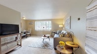 The Columbus Park model unit in Bedford Heights, Ohio presents a thoughtfully laid-out single-floor residence designed for comfortable everyday living. The open living and dining area is generously proportioned, featuring wall-to-wall carpeting, neutral-toned walls, and a large window that allows natural light to fill the space. A wall-mounted air conditioning unit and baseboard heating ensure year-round comfort. The living room flows naturally into a dedicated dining area, creating an inviting space for both relaxing and entertaining.

The kitchen is efficiently designed with warm wood cabinetry, granite-style countertops, tile flooring, and a full suite of appliances including a refrigerator, dishwasher, and range. Ample cabinet storage makes the most of the available space.

The primary bedroom is carpeted and well-lit by a large window, offering a calm and restful retreat. The second bedroom, also carpeted with a window, includes a built-in closet with shelving, providing practical storage. Both rooms maintain a clean, neutral aesthetic throughout.

The bathroom features classic white tile work on the walls and mosaic tile flooring, a tub-shower combination, a white vanity with granite-style countertops, and a framed mirror. The overall ambiance of the unit is clean, bright, and move-in ready.
