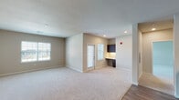Located at 90 Compassion Circle in Wentzville, Missouri, this single-floor unit offers a thoughtfully designed layout with modern finishes throughout. The kitchen is a standout feature, showcasing rich dark cabinetry paired with crisp white countertops and a full suite of stainless steel appliances, including a range, microwave, dishwasher, and refrigerator. Durable wood-style flooring runs through the kitchen and adjoining areas, lending a clean, contemporary feel. The open living area is generously sized, bathed in natural light from multiple windows, and finished with plush neutral carpeting. A built-in desk with overhead dark cabinetry provides a dedicated workspace, while a glass-panel door offers direct outdoor access. The bedrooms are carpeted and well-proportioned, each featuring natural light from exterior windows and access to walk-in closets with built-in shelving. The bathroom is equipped with a dual vessel-sink vanity set atop dark cabinetry, complemented by a large mirror and bright overhead lighting. Neutral warm-toned walls and consistent trim details create a cohesive and inviting atmosphere throughout the entire space.