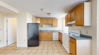 This two-floor residence offers a well-organized layout across two levels, featuring three bedrooms, four bathrooms, a kitchen, a living room, two hallways, and a dedicated closet. The lower level houses the kitchen and living area, where light hardwood and tile flooring define the open feel. The kitchen is fully equipped with warm honey-toned cabinetry, dark granite-style countertops, a black refrigerator, white electric range, dishwasher, and an under-cabinet range hood — all set on classic light tile flooring. Multiple windows on the lower level bring in generous natural light and offer exterior views. A staircase connects to the upper floor, which is more expansive and hosts the bedrooms and bathrooms. The bedrooms feature light hardwood floors, ceiling fans, and large windows that frame outdoor views, creating bright and airy retreats. The spacious primary bedroom includes a dedicated closet with built-in wire shelving. The bathrooms are well-appointed, with one featuring classic penny tile flooring, a wood vanity with dual mirrors, and another showcasing a jetted soaking tub with a white tile surround accented by navy tile trim. Throughout, the warm neutral palette and consistent wood flooring lend the space a cohesive, comfortable character.
