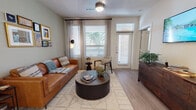 This single-story residence offers a thoughtfully designed layout that balances comfort and modern style throughout its key living spaces. The living room serves as a welcoming focal point, featuring wood-style flooring, soft sage-green walls, and generous natural light streaming through large windows dressed with sheer curtains and blinds. A ceiling fan overhead and direct access to an exterior door enhance both function and airflow.

The kitchen is a standout space, outfitted with dark gray cabinetry, granite-style countertops, a subway tile backsplash, and a full suite of stainless steel appliances. A central island with pendant lighting above doubles as a dining and prep area, connecting seamlessly to the rest of the living space.

The primary bedroom features a bold teal accent wall, plush carpeting, a ceiling fan, and a window with outdoor views. Its en-suite bathroom includes a granite vanity, a glass-enclosed shower, a soaking tub, and direct access to a spacious walk-in closet. A secondary bedroom offers carpeted flooring and a bright window. An additional bathroom features a granite vanity and tub-shower combination, maintaining consistent finishes throughout.