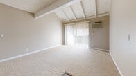 Located in Brea, CA, this 2-bedroom, 2-bathroom residence offers a well-organized single-level layout designed for comfortable everyday living. The living room is an immediate standout, featuring striking vaulted ceilings with exposed white wood beams that lend architectural character and a sense of openness. Sliding glass doors lead out to a private balcony, filling the space with natural light. The galley-style kitchen is thoughtfully designed with white cabinetry, dark granite countertops, black appliances, a built-in dishwasher, and wood-look flooring — with a pass-through window connecting it to the adjacent dining area. A pantry provides additional storage convenience. The spacious primary bedroom features plush carpeting, a mirrored sliding-door closet, and windows that invite natural light. The second bedroom also offers comfortable proportions with carpet flooring and ample wall space. Both bathrooms are finished with white cabinetry, dark granite countertops, and tub-shower combinations. Throughout the home, a warm neutral color palette, white trim, and textured ceilings create a cohesive and inviting ambiance. Three closets across the unit ensure generous storage throughout.