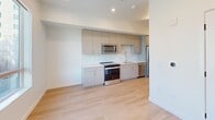 This 260 square foot studio apartment in Salt Lake City offers a thoughtfully designed living space. The open-concept layout maximizes efficiency, seamlessly blending the living area with a modern kitchen. The kitchen boasts sleek, light-colored cabinetry, stainless steel appliances including a refrigerator, stove, and built-in microwave, and a stylish backsplash. Light wood flooring throughout adds warmth and continuity to the space.

The bathroom features a glass-enclosed shower, modern vanity, and toilet, with the same wood flooring as the main living area. Large windows in the living space provide ample natural light and offer views of the surrounding cityscape, including nearby buildings and construction.

Recessed lighting throughout contributes to the apartment's bright, airy feel. The white walls and neutral color palette create a clean, contemporary aesthetic. Despite its compact size, the apartment's thoughtful design ensures functionality and comfort in an urban setting.