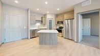 Located at 3509 S Broadway St in Alexandria, Minnesota, this well-designed single-floor unit offers 3 bedrooms and 2 bathrooms across a thoughtfully arranged floor plan. The open-concept kitchen and living area serves as the heart of the unit, featuring light wood cabinetry, stainless steel appliances including a refrigerator, range, microwave, and dishwasher, and a central island with a striking marble-look countertop. A frosted glass pantry door adds a stylish architectural detail to the kitchen. Light luxury vinyl plank flooring runs throughout the main living areas, lending a clean, contemporary aesthetic. The living room is bright and airy, with a large window offering outdoor views and access to an exterior door. The three bedrooms are carpeted for comfort, with neutral toned walls and windows that bring in natural light. The primary bedroom is generously sized and connects to a bathroom. The bathrooms feature wood-toned vanities, white countertops, and light flooring, with one bathroom including a walk-in shower equipped with grab bars. A dedicated in-unit laundry room includes a full-size washer and dryer alongside overhead cabinetry and a countertop for added functionality. The overall design is modern and cohesive, with a neutral palette throughout.