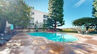 Located in the prestigious Bel Air neighborhood of Los Angeles, this efficiently designed one-bedroom, one-bathroom unit offers a well-planned layout with modern finishes throughout. The open-concept living and sleeping area is anchored by warm light oak hardwood flooring that runs continuously through the space, complemented by crisp white walls and recessed lighting that keep the interior bright and inviting.

The kitchen is a standout feature, outfitted with white shaker-style cabinetry, a striking marble-look quartz backsplash and countertops, stainless steel appliances including a gas range and refrigerator, and a peninsula with bar seating for two — ideal for casual dining and entertaining. Built-in custom cabinetry with open shelving and a multi-drawer dresser unit is seamlessly integrated alongside the sleeping area, providing generous storage without sacrificing style.

The bedroom area is spacious and serene, featuring a wall-mounted mini-split HVAC unit for personalized climate control, a natural light source from a side window, and direct access to the unit's private entrance. The bathroom is finished in neutral tones with beige tile flooring, a white quartz vanity, and a full tub and shower enclosed by sliding glass doors. Every detail of this unit reflects clean, contemporary design with practical functionality.