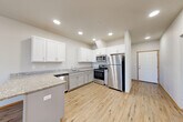 Located at 15037 Tahoma Blvd SE in Yelm, Washington, this single-story, 3-bedroom, 2-bathroom home offers a well-designed, functional layout with modern finishes throughout. Light wood-style vinyl flooring flows continuously across all rooms, complemented by neutral gray and white walls that create a clean, bright atmosphere.

The open kitchen is a standout feature, showcasing white shaker-style cabinetry, granite-look countertops, a kitchen island with additional counter space, and a full suite of stainless steel appliances including a refrigerator, gas range, microwave, and dishwasher. Recessed lighting illuminates the space efficiently.

The combined living area benefits from natural light provided by windows facing the exterior. Hallways connect the bedrooms and bathrooms, maintaining a practical flow throughout the home. The primary bedroom is a comfortable size and includes closet storage. Additional bedrooms share similar finishes, each with light flooring and access to natural light.

Both bathrooms feature granite-look vanity tops with undermount sinks, gray cabinetry with brushed nickel hardware, and shower-tub combinations. A dedicated laundry room houses a full-size washer and dryer alongside the water heater, adding everyday convenience to the home's practical design.