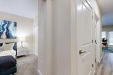 This single-floor unit presents a thoughtfully designed layout that balances functionality with contemporary style. The kitchen serves as a visual centerpiece, showcasing a two-tone cabinetry scheme with crisp white upper cabinets and bold navy lower cabinets, complemented by light quartz countertops, a subway tile backsplash, and a full suite of stainless steel appliances including a refrigerator, range, microwave, and dishwasher. The kitchen flows directly into the living area, creating an open, connected feel ideal for everyday living.

The living space features light wood-look plank flooring and large windows fitted with horizontal blinds, allowing natural light to fill the room. A secondary flexible space, suitable as a home office or dining area, sits adjacent and also benefits from generous window exposure overlooking an outdoor structure.

The bedroom offers plush carpeting, a large window with roller shade and drape treatments, and a relaxed, comfortable ambiance. The full bathroom is finished with wood-look flooring, a wide white vanity with an extended mirror, and a full tub-shower combination.

A carpeted hallway connects the private areas of the unit, featuring textured walls, white panel doors with brushed hardware, and clean, neutral tones throughout.