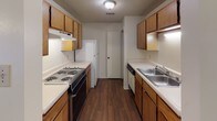This single-floor residence offers a practical and well-organized layout across three bedrooms and two full bathrooms. The living area features neutral walls, a ceiling fan with light fixture, and a sliding glass door with vertical blinds that fills the space with natural light. Durable wood-style flooring runs through the main living and kitchen areas, while plush carpet covers each of the bedrooms.

The galley-style kitchen is efficiently designed with warm wood cabinetry, ample upper and lower cabinet storage, white countertops, a double-basin stainless steel sink, a dishwasher, and a coil-burner electric range with oven. The kitchen flows conveniently toward a dedicated utility or storage area.

Each of the three bedrooms is carpeted and finished with neutral tones, textured ceilings, and adequate closet space — one bedroom features an open reach-in closet with a hanging rod, while another benefits from a window with natural light. The bedrooms offer a clean and versatile canvas for a variety of furnishing arrangements.

Both bathrooms are equipped with a tub-shower combination, toilet, and a single-sink vanity with wood cabinetry. One bathroom features wood-style flooring and a large wall mirror above the vanity. Overall, the home presents a clean, straightforward design suited for comfortable everyday living.