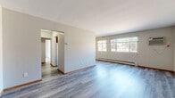 Located at 7232 Portland Ave in Richfield, MN, this 2-bedroom, 1-bathroom unit offers a functional and well-organized single-floor layout. The open living area is a standout feature, showcasing light gray luxury vinyl plank flooring that runs throughout the main living spaces, neutral-toned walls, and a large multi-pane window that allows generous natural light to fill the room. A baseboard heating unit and wall-mounted air conditioning unit provide year-round climate control.

The galley-style kitchen is efficiently designed with rich dark brown cabinetry lining both walls, granite-look countertops, a double-basin sink, and white appliances including an electric range and refrigerator. A ceiling fan adds to the kitchen's functionality. The kitchen connects directly to the hallway and living area for easy flow throughout the unit.

Both bedrooms feature soft carpeting, neutral walls, and windows with views of the surrounding neighborhood. The primary bedroom includes a sliding wood-panel closet door, offering practical storage. The full bathroom is finished with classic white square tile surrounding a full bathtub and shower, a dark wood vanity, a mirrored medicine cabinet, and mosaic tile flooring, creating a clean, timeless aesthetic throughout.
