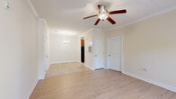 Located at 5001 Ballantyne Drive in Simpsonville, SC, this well-appointed one-bedroom, one-bathroom unit offers a thoughtfully designed single-floor layout. The living room is a welcoming space featuring light wood-style flooring, crown molding, and a ceiling fan with a light fixture, creating a bright and comfortable atmosphere. An open sightline connects the living area to the kitchen, which is outfitted with warm wood cabinetry, granite countertops, tile flooring, and black appliances including a refrigerator, electric range, and microwave. A pendant chandelier adds a refined touch to the adjoining dining area, which benefits from large windows that invite natural light and outdoor views. The bedroom is a generously sized retreat with light wood flooring, access to a dedicated closet, and a door that opens toward the living space. The full bathroom includes a tub-shower combination and tile flooring. A separate laundry room with washer and dryer connections and overhead wire shelving adds everyday convenience. Throughout the unit, neutral warm tones, white trim, and consistent flooring choices contribute to a clean, cohesive aesthetic that is both functional and inviting.