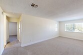 Located at 6001 Auburn St in Bakersfield, CA, this single-story, 2-bedroom, 2-bathroom home offers a practical and well-organized layout. The interior features a neutral color palette with cream-toned walls, textured ceilings, and soft carpet throughout the living and bedroom areas, while light ceramic tile flooring runs through the kitchen and bathrooms.

The kitchen is equipped with warm oak cabinetry, granite-patterned countertops, a white electric range, dishwasher, and refrigerator, complemented by a window that allows natural light to brighten the space. The kitchen flows directly into the adjacent dining area, creating a convenient combined living and eating space.

The spacious primary bedroom features plush carpeting, a window with views of the surrounding greenery, and direct access to the hallway. The second bedroom also includes carpeted floors, a closet, and a window with natural light. Both bedrooms are served by two full bathrooms, each appointed with tile flooring, granite-patterned countertops, white cabinetry, and a bathtub/shower combination.

Additional highlights include a dedicated laundry area, two closets for ample storage, and a central hallway connecting all rooms. The home's efficient single-floor layout ensures seamless accessibility throughout.