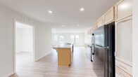 Located on 3rd St SW in Kasson, Minnesota, this single-floor residence offers four bedrooms, two bathrooms, and a well-designed layout that maximizes functionality. The open-concept kitchen and living area serves as the heart of the home, featuring light maple cabinetry, granite countertops, a central island with a sink and breakfast bar overhang, and black stainless appliances including a refrigerator, range, microwave, and dishwasher. Recessed lighting illuminates the space, while light-toned luxury vinyl plank flooring runs consistently throughout, contributing to a clean, cohesive aesthetic. The living area is bathed in natural light through multiple windows and provides direct access to a private balcony. The four bedrooms are well-proportioned, with the primary bedroom offering generous space, and all rooms benefit from ample closet storage—five closets total across the unit. The two bathrooms are finished in a bright, neutral palette, with one featuring a full tub-shower combination equipped with accessible grab bars. A dedicated laundry room houses a full-size side-by-side GE washer and dryer with overhead shelving. The overall ambiance is fresh, modern, and move-in ready.