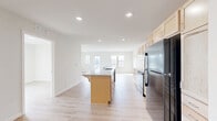Located on 3rd St SW in Kasson, Minnesota, this single-floor residence offers four bedrooms, two bathrooms, and a well-designed layout that maximizes functionality. The open-concept kitchen and living area serves as the heart of the home, featuring light maple cabinetry, granite countertops, a central island with a sink and breakfast bar overhang, and black stainless appliances including a refrigerator, range, microwave, and dishwasher. Recessed lighting illuminates the space, while light-toned luxury vinyl plank flooring runs consistently throughout, contributing to a clean, cohesive aesthetic. The living area is bathed in natural light through multiple windows and provides direct access to a private balcony. The four bedrooms are well-proportioned, with the primary bedroom offering generous space, and all rooms benefit from ample closet storage—five closets total across the unit. The two bathrooms are finished in a bright, neutral palette, with one featuring a full tub-shower combination equipped with accessible grab bars. A dedicated laundry room houses a full-size side-by-side GE washer and dryer with overhead shelving. The overall ambiance is fresh, modern, and move-in ready.