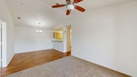 Located at 1015 Fairwinds Cir in Plant City, Florida, this single-floor home offers a well-organized layout designed for comfortable everyday living. The open-concept living and dining area is a standout feature, boasting vaulted ceilings that lend a sense of spaciousness and airiness to the space. A ceiling fan with light kit and an elegant chandelier complement the area, while wood-look flooring in the dining zone transitions seamlessly to plush carpet in the living area. A pass-through counter connects the living space to the kitchen, which is equipped with light wood cabinetry, laminate countertops, a coil-top electric range, and a full-size refrigerator — all finished in white for a clean, cohesive look. A wide hallway with louvered closet doors provides practical storage and leads to the private quarters of the home. The bedrooms are generously proportioned, each featuring soft carpet flooring and windows fitted with blinds that allow natural light to fill the rooms. Two full bathrooms serve the home — one featuring a vanity with light wood cabinetry and stone-tone countertop, and both offering tiled tub-shower combinations and wood-look flooring. The overall aesthetic is bright, neutral, and move-in ready.