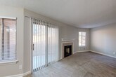 This single-floor, one-bedroom, one-bathroom unit is efficiently laid out across a compact but functional footprint. The living room serves as the centerpiece of the space, featuring a fireplace with a white mantle, a large sliding glass door fitted with vertical blinds that allows natural light to fill the room, and an additional window. Carpet flooring and a textured ceiling complete the room's neutral, understated aesthetic. An adjoining area with a chandelier overhead provides space suitable for dining.

The hallway connects the main living areas to the bedroom and bathroom, featuring wood-look vinyl flooring and a louvered closet door for storage. The bedroom is comfortably sized, offering carpet flooring, a large window with outdoor views of surrounding greenery, and clean, neutral walls.

The kitchen is galley-style with white raised-panel cabinetry, a subway tile backsplash, light stone-look countertops, and light wood-look flooring. Stainless steel appliances, including a refrigerator, range, and over-the-range microwave, are included.

The bathroom features a full tub-shower combination with a grab bar, a built-in shelf niche, and a clean white surround, complemented by wood-look flooring.