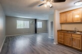 Located at 1540 W Ball Rd in Anaheim, California, this single-floor unit offers a functional and well-organized layout comprising an open-concept kitchen and living area, plus one full bathroom. Light wood-style laminate flooring runs throughout the entire space, lending a clean, cohesive look that brightens each room.

The combined kitchen and living area forms the heart of the unit. The kitchen is outfitted with warm honey-toned wood cabinetry offering generous upper and lower storage, a double-basin sink with granite-look countertops, and a stainless steel gas range. A ceiling fan with integrated lighting fixture overhead provides both air circulation and ambient light. The living area flows naturally from the kitchen and features a wall-mounted air conditioning unit alongside a vertical-slat window covering that filters in natural light, keeping the space comfortable year-round. A textured popcorn ceiling adds a classic residential character throughout.

The bathroom is clean and straightforward, featuring a single-vanity with wood cabinetry, a toilet, and a full shower-tub combination with a curtain rod. Light neutral wall tones carry through from the main living areas, maintaining a consistent and airy aesthetic.

Overall, this unit presents a practical, move-in-ready space with a neutral palette and efficient use of its compact footprint, ideally suited for those seeking a manageable, low-maintenance living environment in Anaheim.