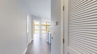 Located at 3549 Georgia Ave NW in Washington, DC, this single-floor unit offers a thoughtfully designed layout comprising a living room, kitchen, hallway, and two full bathrooms. The kitchen is a standout feature, showcasing gray shaker-style cabinetry, quartz countertops, a center island with an undermount sink, and a herringbone-patterned tile backsplash. Stainless steel appliances, including a French door refrigerator and a double oven range, are complemented by a stainless steel range hood and elegant pendant lighting above the island. Wood-look luxury vinyl plank flooring flows throughout, adding warmth and continuity. The two bathrooms are finished to a high standard, each featuring marble-look tile flooring, tub-shower combinations with full tile surrounds, built-in niche shelving, and gray vanities with brushed nickel or gold hardware. The living area is bright and open with neutral gray walls and abundant natural light. The hallway connects the spaces efficiently, maintaining a clean, modern aesthetic throughout. The overall design palette — soft grays, whites, and natural wood tones — creates a cohesive, contemporary ambiance well-suited for urban living in the vibrant Georgia Avenue corridor.