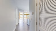 Located at 3549 Georgia Ave NW in Washington, DC, this single-floor unit offers a thoughtfully designed layout comprising a living room, kitchen, hallway, and two full bathrooms. The kitchen is a standout feature, showcasing gray shaker-style cabinetry, quartz countertops, a center island with an undermount sink, and a herringbone-patterned tile backsplash. Stainless steel appliances, including a French door refrigerator and a double oven range, are complemented by a stainless steel range hood and elegant pendant lighting above the island. Wood-look luxury vinyl plank flooring flows throughout, adding warmth and continuity. The two bathrooms are finished to a high standard, each featuring marble-look tile flooring, tub-shower combinations with full tile surrounds, built-in niche shelving, and gray vanities with brushed nickel or gold hardware. The living area is bright and open with neutral gray walls and abundant natural light. The hallway connects the spaces efficiently, maintaining a clean, modern aesthetic throughout. The overall design palette — soft grays, whites, and natural wood tones — creates a cohesive, contemporary ambiance well-suited for urban living in the vibrant Georgia Avenue corridor.