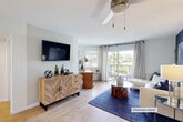 Located in Boca Raton, FL, this thoughtfully designed one-bedroom, one-bathroom residence offers an efficient yet comfortable single-floor layout with cohesive modern-meets-natural interior styling throughout.

The living room serves as the heart of the home, featuring light wood-look flooring, a ceiling fan, and a wall-mounted television above a reclaimed wood herringbone-patterned credenza. Sliding glass doors open to a private balcony with outdoor views, flooding the space with natural light. The living area connects seamlessly to a dedicated dining room, which features a large wall mirror that amplifies the sense of space and reflects the adjoining rooms.

The galley-style kitchen is outfitted with white cabinetry, white countertops, stainless steel appliances including a full-size refrigerator, and light tile flooring. A dedicated pantry with louvered doors provides additional storage adjacent to the dining area.

The bedroom features a bold navy accent wall, light wood flooring, a walk-in closet area, and a window with garden views. The full bathroom includes a wide white vanity with ample cabinetry, a wood-framed mirror, blue accent walls, and a shower-tub combination with a window for natural light.