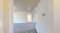 Located at 7016 Park Heights Ave in Baltimore, MD, this single-floor unit offers a well-organized layout with multiple rooms finished in neutral tones throughout. The living area features plush gray carpeting, crisp white baseboards, and a wall-mounted thermostat, providing a clean and functional foundation. Ceiling-mounted HVAC vents are present throughout, ensuring consistent climate control across the space.

Several generously sized rooms feature gray wall-to-wall carpeting and large double-hung windows dressed with blinds, allowing natural light to fill each space. One room includes a closet, adding practical storage. The dining area is distinguished by a classic globe pendant light fixture and a window overlooking the exterior.

The unit includes two bathrooms. The full bathroom features a classic black-and-white tile design with a tiled surround tub-shower combination, wood-look flooring, a pedestal-style vanity, and a natural light window. The second bathroom offers a white vanity with cabinet storage, a mirror with overhead lighting, and a window for ventilation.

Overall, the space presents a clean, move-in ready environment with a consistent neutral palette and ample natural light throughout.