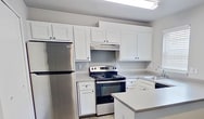 Located on NE Eighth St in Gresham, OR, this single-floor, 2-bedroom, 1-bathroom unit spans 690 square feet of efficiently designed living space. The kitchen is a standout feature, equipped with stainless steel appliances including a refrigerator and electric range, white shaker-style cabinetry, light countertops, and wood-look vinyl plank flooring. A peninsula counter provides additional workspace and separates the kitchen from the adjoining living area. Natural light enters through a window with blinds, complementing the overhead fluorescent lighting. The full bathroom features a single-sink vanity with white cabinetry, a toilet, and a tub/shower combination with clean white surround, all set on wood-look vinyl plank flooring. Both bedrooms are carpeted and finished in neutral gray tones with white baseboards. The primary bedroom measures 130 square feet and includes a sliding-door closet with built-in shelving. The second bedroom also features a window with blinds and baseboard heating. Both rooms offer a clean, move-in-ready aesthetic. The unit's consistent neutral palette and updated fixtures create a cohesive, practical living environment suitable for a variety of occupants.