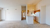 Located at 1078 Raven Pl in Wadsworth, Ohio, this single-floor, two-bedroom, one-bathroom home offers a functional and comfortable layout. The open-concept living and kitchen area is immediately welcoming, featuring vaulted ceilings that lend a sense of height and openness. The living room is carpeted and bathed in natural light through large vertical-blind-covered sliding glass doors. The kitchen is well-appointed with warm wood cabinetry, white appliances including a dishwasher, electric range, and refrigerator, complemented by tile flooring and a pendant light fixture above a breakfast bar-style peninsula. A hallway connects the main living areas to the two bedrooms and bathroom. The primary bedroom is generously sized, featuring carpet flooring, a ceiling fan, a window for natural light, and a walk-in closet with wire shelving. The second bedroom also offers carpet, dual windows, a ceiling fan, and a sliding closet. The full bathroom includes a tub/shower combination, vanity with wood cabinetry, tile flooring, and ample wall space. Throughout the home, neutral tones and clean finishes create a bright, move-in-ready atmosphere suited for everyday living.