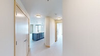 Located at 202 S Pinckney St in the heart of downtown Madison, this modern 2-bedroom, 2-bathroom residence offers a thoughtfully designed single-level layout with contemporary finishes throughout. Light-toned luxury vinyl plank flooring flows seamlessly across the open-concept living, dining, and kitchen areas, creating a bright and cohesive feel. The kitchen is a standout feature, showcasing a large quartz-topped island with an undermount sink, two-tone cabinetry in white and steel blue, a white tile backsplash, and stainless steel appliances, all illuminated by pendant lighting. Floor-to-ceiling windows flood the living areas with natural light and offer impressive views of the downtown Madison skyline. An exposed concrete structural column adds an industrial accent to the living space. The primary bedroom is generously sized, with large windows framing urban views and a ceiling fan for comfort. The second bedroom features clean white walls and light flooring, offering a versatile and bright space. Both bathrooms are finished with wide-format vanities, framed mirrors, and brushed nickel hardware. A dedicated closet and well-distributed floor plan round out this polished urban residence.