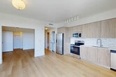 Located at 4465 Griffin Rd in Hollywood, Florida, this thoughtfully designed one-bedroom, one-bathroom residence offers a clean, modern aesthetic throughout its efficiently organized single-floor layout. Light oak hardwood flooring runs continuously through the space, enhancing the bright and airy atmosphere created by crisp white walls and abundant natural light.

The open-concept living area seamlessly integrates the dining and kitchen spaces, creating an inviting environment for both daily living and entertaining. The kitchen is outfitted with light wood cabinetry extending floor to ceiling, a textured subway tile backsplash, white quartz countertops, and a full suite of stainless steel appliances including a French door refrigerator, electric range, microwave, and dishwasher. Track lighting above the kitchen adds a contemporary touch.

The living area opens directly to a private balcony through large floor-to-ceiling sliding glass doors, framing expansive green outdoor views — a standout feature of the space. The bedroom is a well-proportioned, serene retreat with access to a dedicated closet. A hallway connecting the rooms also provides additional closet storage and in-unit laundry access. The bathroom features a soaking tub and shower combination finished with large-format marble-style tile, offering a clean, spa-inspired feel.