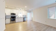 Located at 530 W Town St in Columbus, Ohio, this modern single-floor unit offers a clean, contemporary design with an open-concept layout and thoughtfully selected finishes. Light-toned hardwood-style flooring runs throughout the main living areas, creating a bright and cohesive aesthetic.

The open living and dining area flows seamlessly into the kitchen, which is equipped with sleek white cabinetry, white subway tile backsplash, gray countertops, and a full suite of stainless steel appliances including a range, microwave, dishwasher, and refrigerator. A bold blue pendant light and track lighting above add a modern accent to the kitchen space.

A carpeted bedroom provides a comfortable retreat, featuring a glass-paneled exterior door that invites natural light. The unit includes two bathrooms: one with a glass-enclosed walk-in shower featuring vertically laid gray tile, and a second with a full soaking tub and shower combination, both with wood-look tile flooring and white vanities with gray countertops.

Additional features include an in-unit laundry closet, generous storage, and a welcoming entry area. The overall design emphasizes clean lines, neutral tones, and practical modern living in the heart of Columbus.