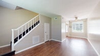 This two-story home in Memphis, Tennessee offers a functional and comfortable layout across two floors. Rich hardwood-style flooring flows throughout the main living areas, creating a warm and cohesive aesthetic. The main floor features an open living area filled with natural light from large windows, a ceiling fan for added comfort, and a staircase with classic white railings leading to the upper level. The kitchen is well-appointed with white shaker-style cabinetry, granite-look countertops, a subway tile backsplash, and black appliances including a gas range, microwave, and refrigerator. A door in the kitchen provides convenient exterior access. Upstairs, two bedrooms each feature hardwood-style floors, neutral tones, built-in closets, and bright windows with outdoor views of surrounding greenery. A shared hallway connects both bedrooms to the full bathroom, which showcases floor-to-ceiling white subway tile surrounding a tub-shower combination, a white vanity with storage, and a window that brings in natural light. The thoughtful two-floor layout maximizes privacy, with living and cooking spaces on the ground floor and sleeping quarters above, making this a well-structured and inviting home.