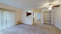This single-floor residential unit offers a practical and well-organized layout designed for comfortable everyday living. The open-concept living area is finished with plush wall-to-wall carpeting and features a ceiling fan, built-in shelving for storage and display, and a pass-through window that connects directly to the kitchen — creating a sense of openness while maintaining defined spaces. Natural light flows through the windows throughout the unit, giving each room a bright and airy feel with views of surrounding greenery.

The galley-style kitchen is a functional highlight of the space, featuring rich dark wood cabinetry, light stone-look countertops, and a full suite of black appliances including a gas range with overhead microwave, refrigerator, and sink. Wood-look flooring runs through the kitchen, adding warmth and easy maintenance underfoot.

The bedroom is generously proportioned, finished with soft carpeting and a large window that brings in ample natural light and treetop views, creating a calm and restful retreat.

The bathroom is clean and straightforward, featuring a full-size tub and shower combination with white tile surround and chrome fixtures. Throughout the unit, the neutral color palette of whites and warm beiges provides a versatile, move-in-ready canvas.