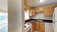 This single-story 2-bedroom, 1.5-bathroom residence offers a practical and well-organized layout designed for comfortable everyday living. The kitchen is a standout feature, showcasing warm honey-toned wood cabinetry that lines both the upper and lower walls, providing generous storage space. Dark granite-style countertops contrast neatly with the light cabinetry, lending the kitchen a clean and classic aesthetic. A white electric range and a stainless steel sink are efficiently positioned within the compact but thoughtfully arranged workspace. A window above the counter area allows natural light to filter in, brightening the cooking space. The neutral wall tones throughout create a calm, versatile backdrop that complements a variety of décor styles. The half bath adds everyday convenience for guests, while the two bedrooms offer comfortable private retreats. The overall layout is designed with functionality in mind, making efficient use of the available space on a single level. This home presents a straightforward, well-maintained living environment suited to a range of lifestyles.