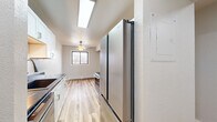 This thoughtfully designed 2-bedroom, 1-bathroom unit in East Grand Forks, Minnesota, offers a clean, modern aesthetic throughout its single-floor layout. Light-toned hardwood-style flooring runs continuously through every room, creating a cohesive and bright ambiance.

The galley-style kitchen is a standout feature, showcasing white shaker cabinetry, striking black marble-look countertops, stainless steel appliances including a refrigerator, microwave, and range, plus a skylight overhead that floods the space with natural light. The kitchen flows seamlessly into the adjacent dining area.

The living room is open and airy, highlighted by a classic fireplace with a wood mantle and a window that draws in natural light. A ceiling fan adds to the room's comfort. One bedroom features a sliding glass door that opens directly onto a private balcony, offering outdoor views and additional ventilation via a wall-mounted AC unit. The second bedroom includes a built-in closet organizer with dual hanging rods and shelving, maximizing storage.

With five closets total throughout the unit, storage is plentiful. The bathroom features a full tub-shower combination with built-in shelving and brushed nickel fixtures. The neutral color palette and updated finishes throughout create a clean, move-in-ready environment.