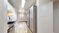 This thoughtfully designed 2-bedroom, 1-bathroom unit in East Grand Forks, Minnesota, offers a clean, modern aesthetic throughout its single-floor layout. Light-toned hardwood-style flooring runs continuously through every room, creating a cohesive and bright ambiance.

The galley-style kitchen is a standout feature, showcasing white shaker cabinetry, striking black marble-look countertops, stainless steel appliances including a refrigerator, microwave, and range, plus a skylight overhead that floods the space with natural light. The kitchen flows seamlessly into the adjacent dining area.

The living room is open and airy, highlighted by a classic fireplace with a wood mantle and a window that draws in natural light. A ceiling fan adds to the room's comfort. One bedroom features a sliding glass door that opens directly onto a private balcony, offering outdoor views and additional ventilation via a wall-mounted AC unit. The second bedroom includes a built-in closet organizer with dual hanging rods and shelving, maximizing storage.

With five closets total throughout the unit, storage is plentiful. The bathroom features a full tub-shower combination with built-in shelving and brushed nickel fixtures. The neutral color palette and updated finishes throughout create a clean, move-in-ready environment.